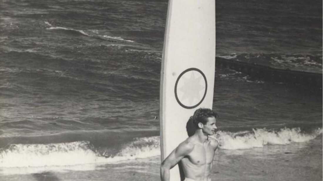 A Florida surfer stands with his board at the water's edge